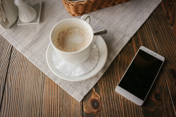 Top view of a smartphone and a Cup of coffee on a rustic wooden table.