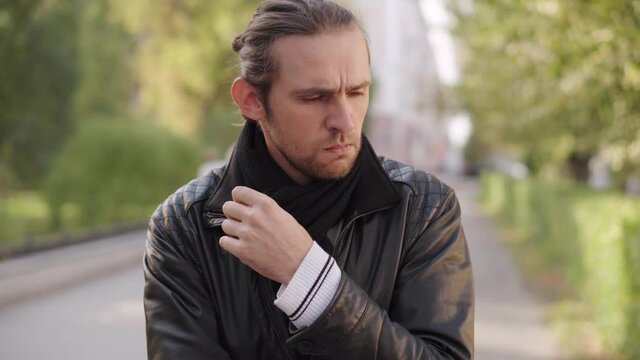 Portrait of a pensive man pondering a problem in a black jacket on a city street. Concept of people and emotions.