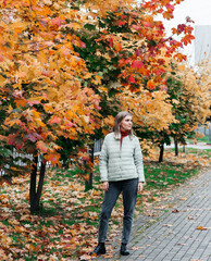 young woman autumn landscape red yellow maple leaves, in an orange knitted warm sweater