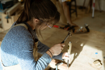 A young female carpenter working as wood designer in a small carpentry workshop. Young business woman handcrafting a piece of timber and designing new house furniture. Entrepreneurs concept lifestyle