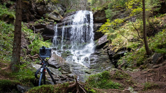 Taking photo of a waterfall. Camera on tripod in front of a waterfall in a forest, near Keprnik mountain, Czech Republic.
