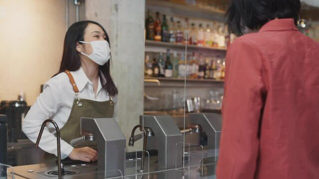 Asian waitress receive food and drink order from caucasian customer.