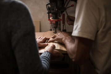 A young couple of carpenter working together in a small wood laboratory using a drill machine for timber. Couple crafting new home furniture in a carpentry workshop. young entrepreneurs concept