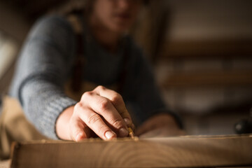 A young female carpenter working as wood designer in a small carpentry workshop. Young business woman handcrafting a piece of timber and designing new house furniture. Entrepreneurs concept lifestyle