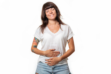 A smiling woman closed her eyes and holds her stomach with hands. White background. Copy space....