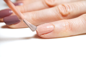 Obraz na płótnie Canvas Manicure. Closeup of a woman hand polishing nails manicure. Nail technician manicure at nail salon. Young caucasian woman receiving a french manicure.