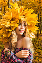 Beautiful girl in a wreath of autumn leaves.