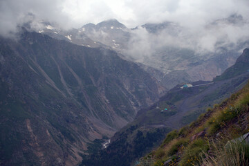 Peaks and slopes of mountains in foggy weather. Elbrus region near the village of Terskol. Caucasus, Russia.