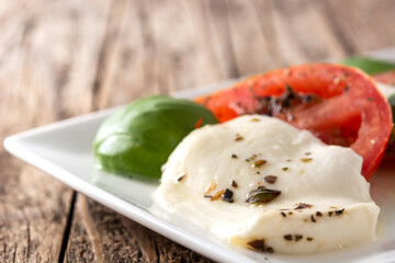 Traditional caprese salad with tomato and mozzarella cheese on wooden table