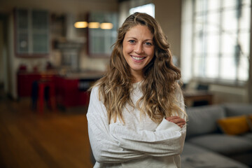 Fototapeta premium Authentic close up shot of an young attractive happy woman is smiling in camera in a living room at home.