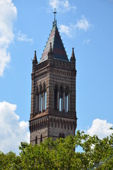 Fototapeta na wymiar The Old South Church Tower in Boston with some trees in forground under a slightly cloudy blue sky