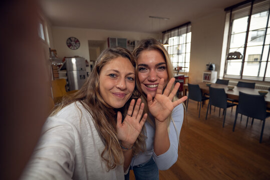 A happy smiling family is making a selfie or video call to friends or relatives while having a breakfast together in a living room at home. - Powered by Adobe