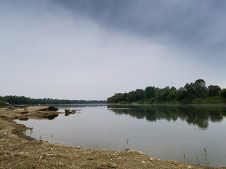 Landscape of the rocky bank of the Sava river during a cloudy gloomy summer day.