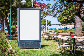 vertical advertising white empty banner in black frame on lawn near street cafe
