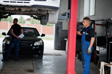 Naklejka premium Car repair and maintenance theme. Mechanic in uniform working in auto service.