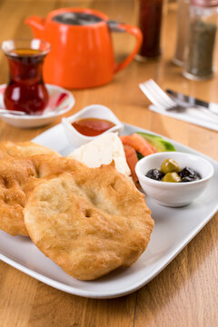 Turkish pisi served with tomatoes, cheese olives and honey on a white plate