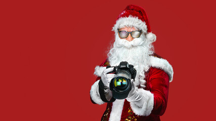 cool Santa Claus taking holiday pictures - isolated on the red background