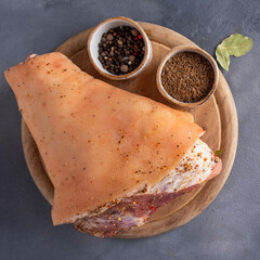 Top view of raw pork knuckle with spices on a wooden board. Closeup