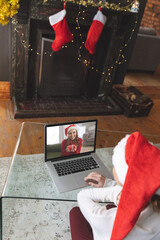 Woman in Santa hat having a video chat with another woman on laptop at home