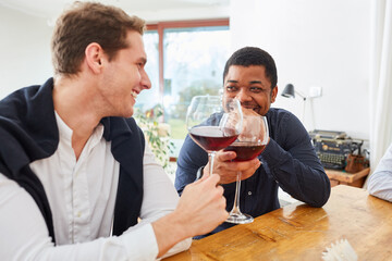 Two men clink glasses of wine at party