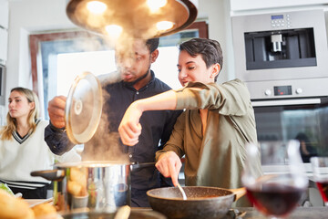 Friends cook pasta with sauce together in shared kitchen