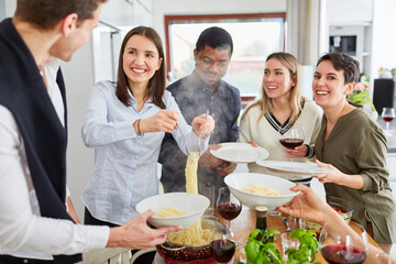 Friends serving spaghetti for a meal together