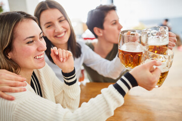 Group of women watch football together and clink glasses of beer
