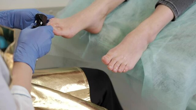 Hardware medical pedicure with nail file drill apparatus. Patient on pedicure treatment with pediatrician chiropodist. Foot peeling treatment at spa with a special device. Clinic of Podiatry Podology.