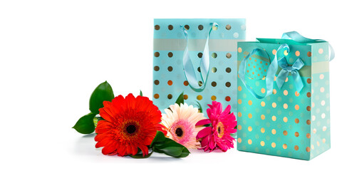 Turquoise paper bag with satin ribbon handles for gift wrapping with a bouquet of gerbera flowers,...