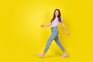 Fototapeta na wymiar Full length body size profile side view of attractive thin cheerful wavy-haired girl going isolated over bright yellow color background