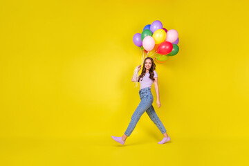 Fototapeta na wymiar Full length body size profile side view of lovely fit cheerful wavy-haired girl going carrying air balls isolated bright yellow color background