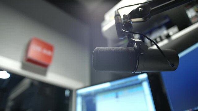 Microphone in a radio studio. DJ moves the microphone, starts broadcasting hot news. Records an evening podcast. Equipment in a recording studio. "ON AIR" sign.