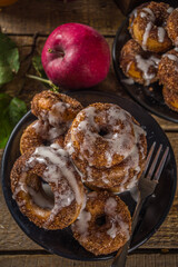 Autumn sweet dessert recipe. Homemade apple cider donuts. Baked donuts with sugar, cinnamon glaze and white sugar topping drizzle, on wooden background with fresh apples