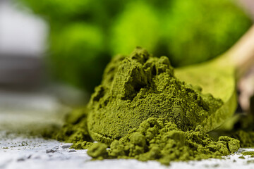 Green powder chlorella, spirulina on gray concrete background. Concept dieting, detox, healthy...