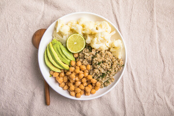 A bowl of healthy vegan and vegetarian lunch or dinner. Salad of fried chickpeas, quinoa, avocado, cauliflower on a light background.Top view, flat lay