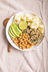 A bowl of healthy vegan and vegetarian lunch or dinner. Salad of fried chickpeas, quinoa, avocado, cauliflower on a light background.Top view, flat lay