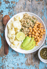 A bowl of healthy vegan and vegetarian lunch or dinner. Salad of fried chickpeas, quinoa, avocado, cauliflower on a light background.Top view, flat lay
