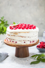 А piece of white cake with milk cream mousse and raspberry filling on a round transparent  stand.