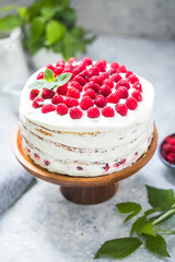 А piece of white cake with milk cream mousse and raspberry filling on a round transparent  stand.
