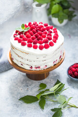 А piece of white cake with milk cream mousse and raspberry filling on a round transparent  stand.