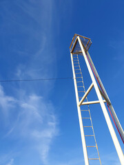 metal tower with a ladder and blue sky on background, selective focus