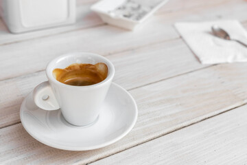 Warm tasty rich italian black espresso coffee cup in white mug on vintage biege wooden rerto style table at cafe or restaurant. Good morning breakfast drink concept. Urban city lifestyle