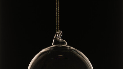 Gläserne Christbaumkugel vor schwarzem Hintergrund mit streiflicht