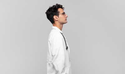 young physician on profile view looking to copy space ahead, thinking, imagining or daydreaming