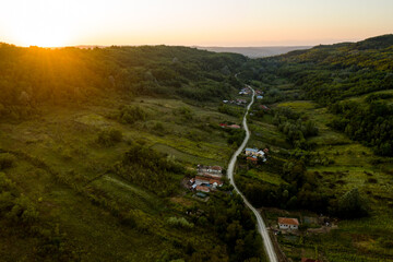 Houses scattered along an unpaved road, at sunset. Aerial view