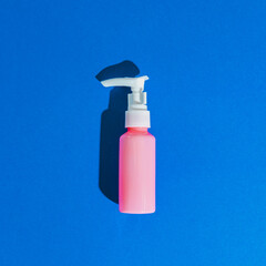 One cosmetic cream for face in blank bottle on blue background. Flat lay, top view, pop art style. Bio organic product.