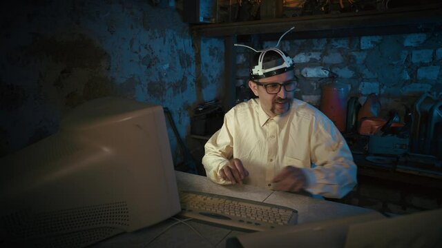 Crazy scientist with stupid glasses records a video message in an old garage. Video conferencing with a funny researcher. Funny programmer with a mustache. Virtual, distance learning, teamwork from ho