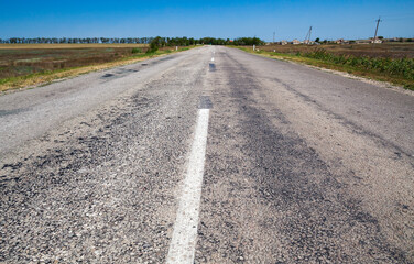 Empty rural highway is under blue sky