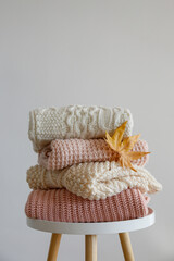 Stack of clean freshly laundered, neatly folded women's clothes on wooden table. Pile of shirts, dresses and sweaters on the table, concrete wall background. Copy space, close up, top view.