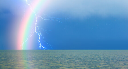 Rainbow over the stormy sea after rain with lightning, calm sea in the foreground